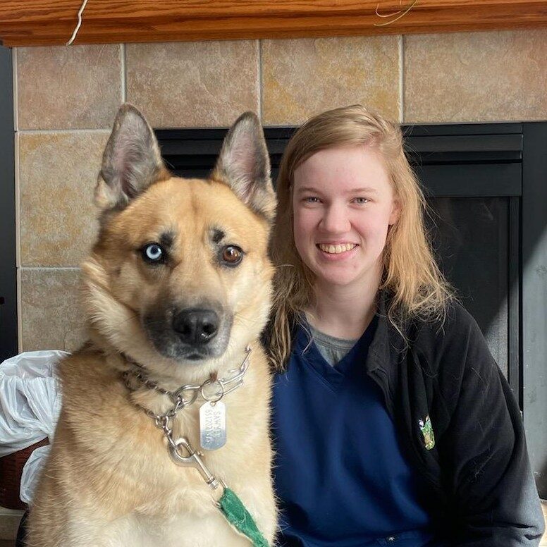 woman smiling sitting next to large dog